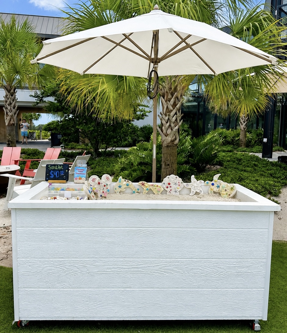 Sand Art station at a resort with colorful keepsakes under a umbrella