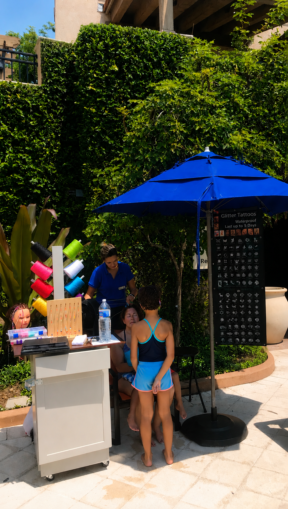 Brena's Arts & Activities poolside braiding and glitter tattoo station at a resort
