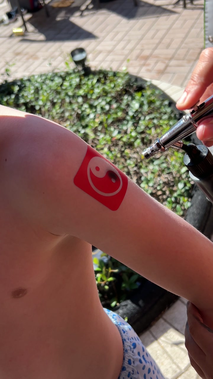Airbrush tattoo being applied at a poolside station